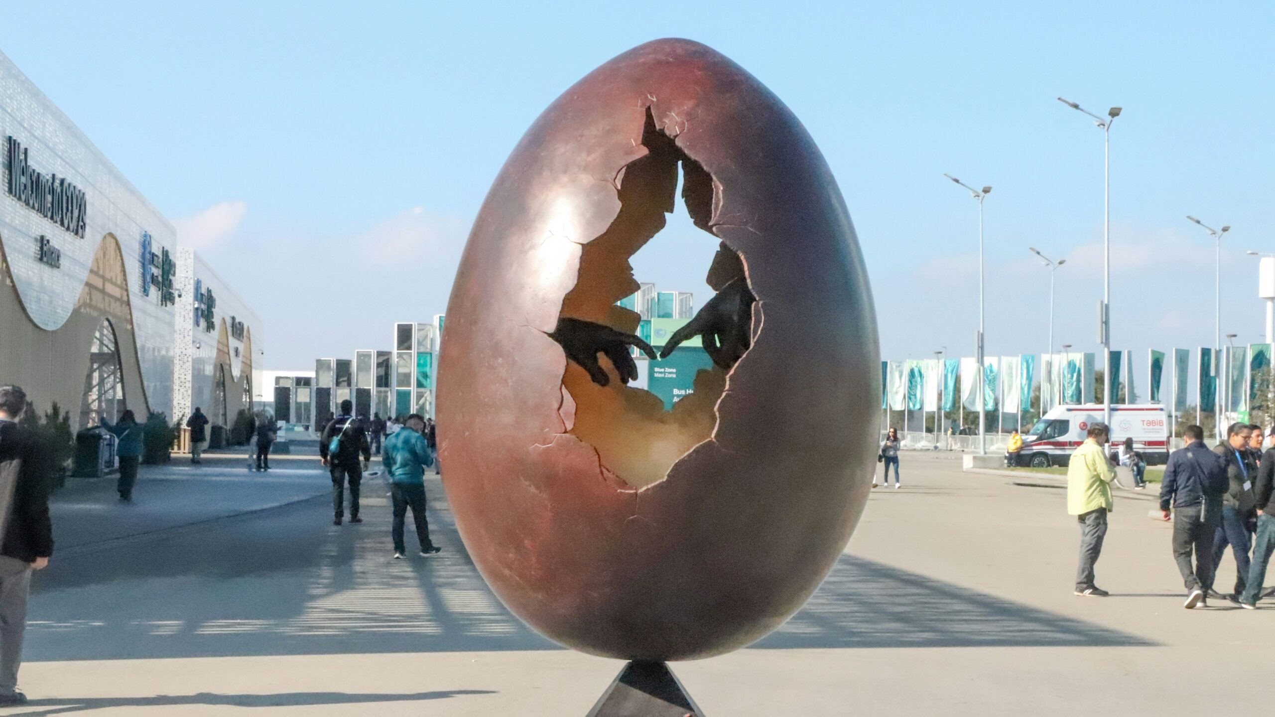 A photo of an hollowed egg sculpture with two hands touching inside