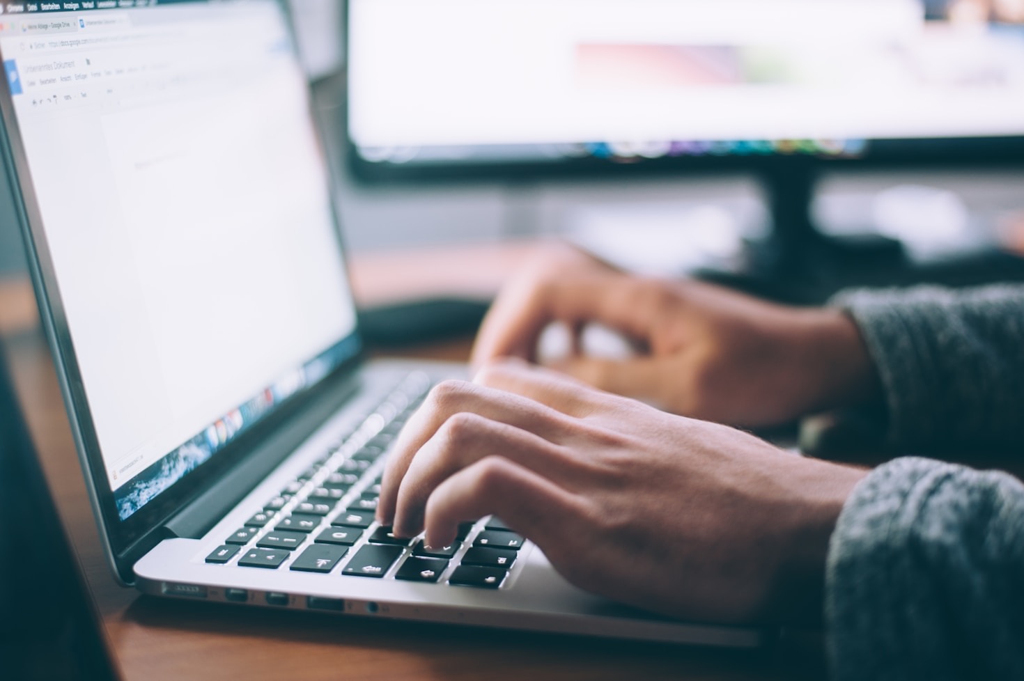 Two hands typing on a laptop.